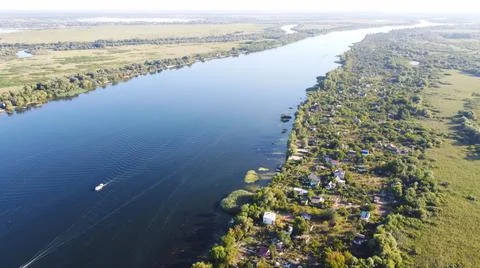 Drone fly over waving river of blue color surrounded by local village with va Stock Photos