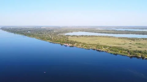 Drone fly over waving river of blue color surrounded by local village with va Stock Photos