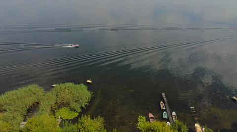 Drone fly over waving river of blue color surrounded by local village with va Stock Photos