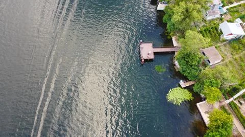 Drone fly over waving river of blue color surrounded by local village with va Stock Photos