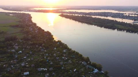 Drone fly over waving river of blue color surrounded by local village with va Stock Photos