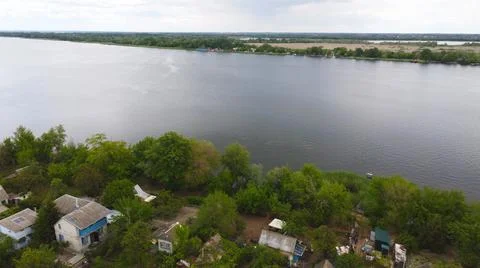 Drone fly over waving river of blue color surrounded by local village with va Stock Photos