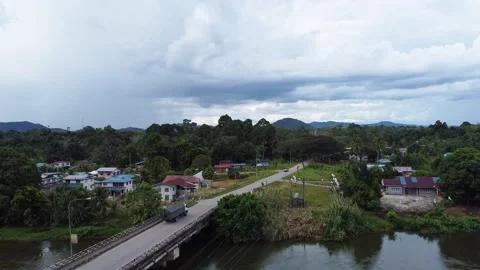 Drone fly-up shot of lorry leaving via a bridge in Lubuk Antu town Stock Footage 239003932