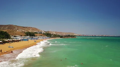 Drone flyby over a beautiful luxury beach resort with rough sea with waves Stock Footage 120426089