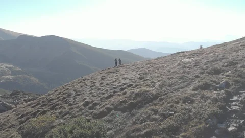 Drone flying above mountains two tourists walking on mountain Stock Footage 104304387