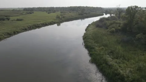 Drone flying above a still river that is winding through a boggy landscape Stock Footage 330363807