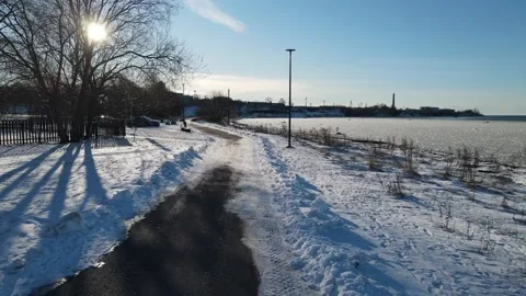 Drone flying above walking path along sea in winter Stock Footage 237916668