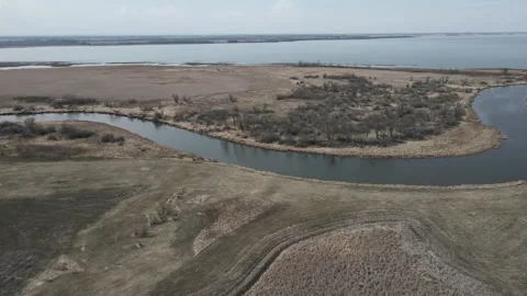 Drone flying above a winding river and over dry mashes next to large lake under Stock Footage 306623097