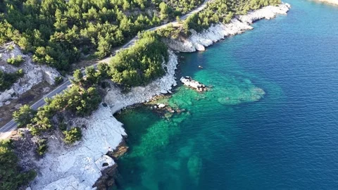 Drone Flying Along Forested Rocky Coast and Clear Sea Stock Footage 340508832
