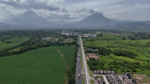 Drone flying along highway through sugarcane fields toward volcanoes Video stock 338180374