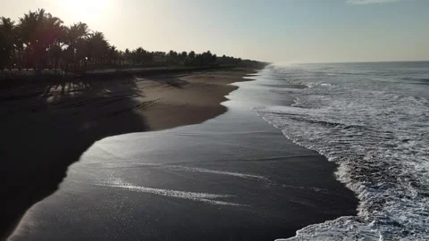 Drone flying along Pacific coastline with black sand beach at sunrise Video stock 339076401