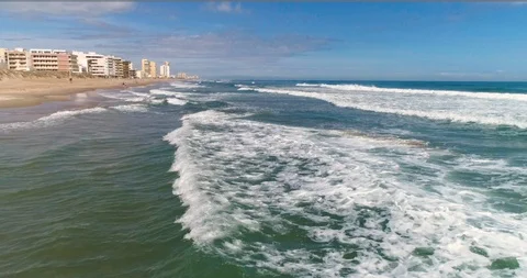 Drone flying along the waves parallel to the coast and coastal town Stock Footage 124374089