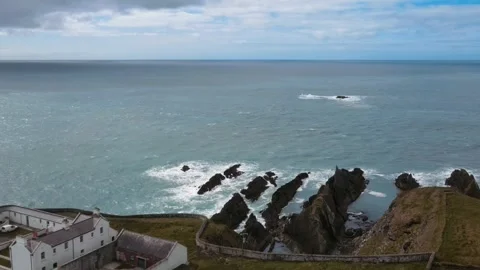 Drone flying along a white lighthouse over rocks in the ocean, Ireland Video stock 267076422