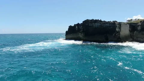 Drone is flying around the massive rocky cliffs along the shore, blue water, 4k Stock Footage 154803267
