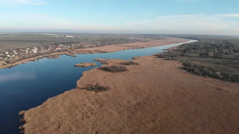 Drone flying back over the river. There are dry grass and reeds on the bank. Stock Footage 157829198