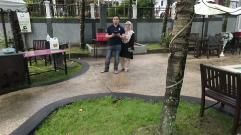 Drone flying backward from couple and passing through coconut tree Stock Footage 149947545