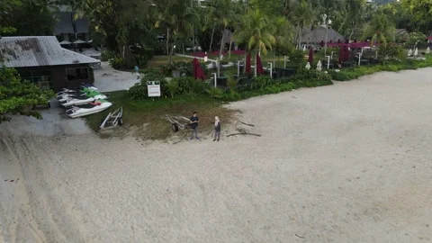 Drone flying backward from couple who is standing on the beach Stock Footage 150110893