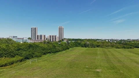 Drone Flying Backward Over Green Park Toward Skyline on a Clear Summer Day Stock Footage 309761992