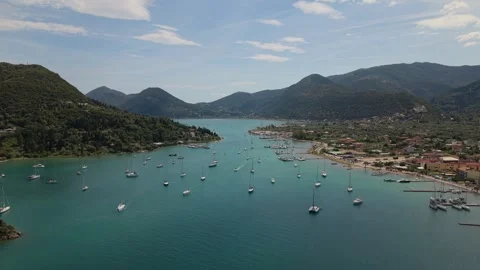 Drone Flying Backward Over Sailboats in Scenic Bay Surrounded by Mountains Stock-Footage 336514201