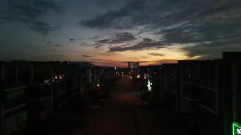 Drone flying backward from sunrise and passing through shops Stock Footage 150112149