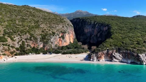 Drone Flying Backward from Wild Beach Revealing Canyon and Turquoise Sea Stock Footage 330883499