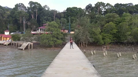Drone flying backwards from a man on the jetty in Pasir Panjang Stock Footage 150721749