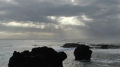 Drone flying backwards over ocean rocks cloudy sun Stock Footage 303639038