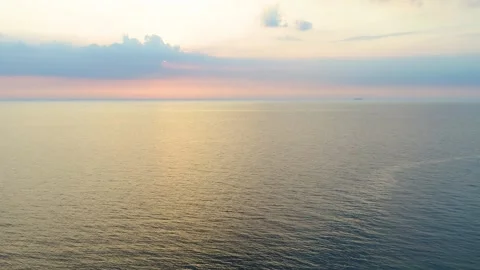 Drone flying backwards over sea and beach at sunset Stock Footage 283072350