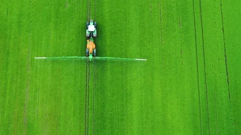 Drone flying backwards over a tractor fertilizing a green field 4K Stock Footage 236723287