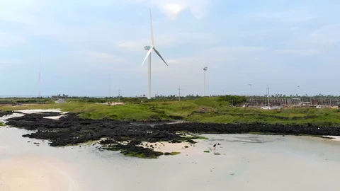 Drone flying from from beach over fields towards windmill wind turbine Video stock 91092285