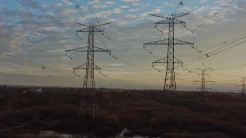 Drone flying between power lines with cloudy blue sky and grassy ground Stock Footage 251241171