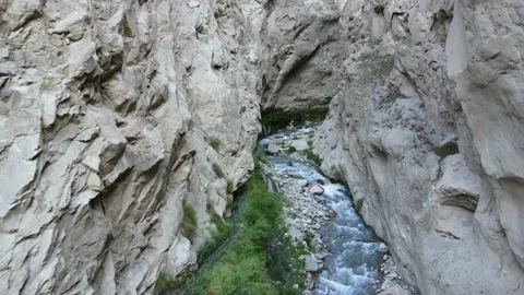 Drone flying between rocks of a narrow gorge and over a small water stream Stock Footage 237388155