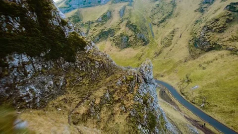 Drone flying between stone cliffs with view of empty road. Rocky landscape in Stock Footage 303169223