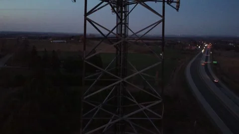 Drone flying up cell tower at sunrise with highway traffic in the background Stock Footage 280009889