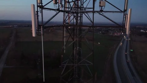 Drone flying up cell tower at sunrise with highway traffic in the background 스톡 동영상 280009927
