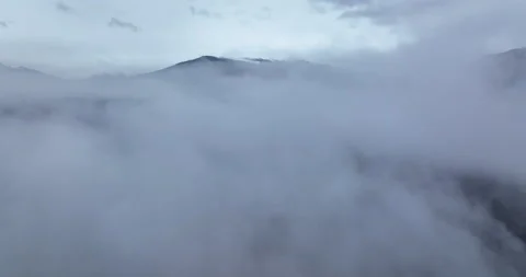 Drone flying in the clouds above the lake revealing the mountain. Winter scenery Stock Footage 174435664