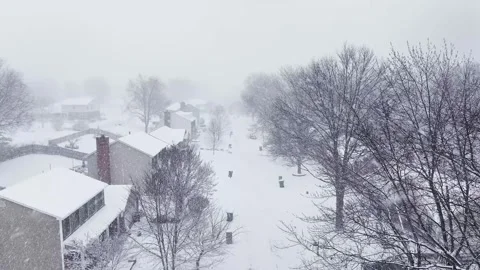 Drone flying down a snow covered neighborhood street during a snow storm. Stock Footage 264983961