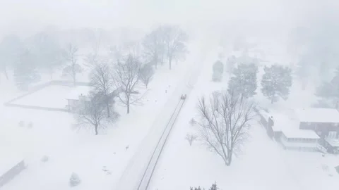 Drone flying down a snow covered neighborhood street during a snow storm. Stock Footage 264992729