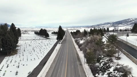 Drone flying down snowy highway outside of a small town Stock Footage 229806440