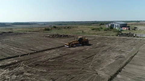 Drone is flying in the field over a massive machine leveling the ground Stock Footage 160115137