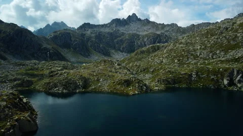 Drone flying forward between two rocky mountains with alpine lakes below Stock Footage 314193083