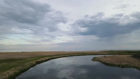Drone flying forward low over a calm winding river that is reflecting the sky Stock Footage 276281243