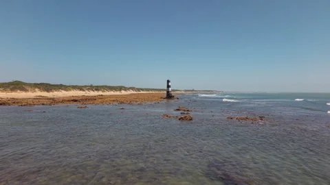 Drone Flying Forward Low Over Water Toward Beacon with Coastline, Gentle Waves,  Stock Footage 306317002