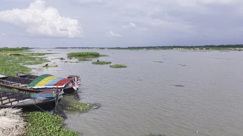 Drone flying forward over boats beside a green rural riverbank Vídeo Stock 344952633