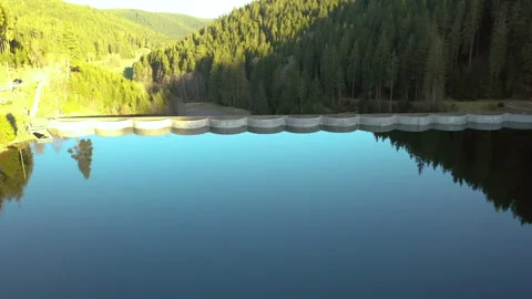 Drone flying forward over calm lake toward dam with reflection, cinematic aerial Video stock 333067751