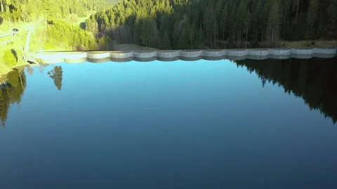 Drone flying forward over calm lake toward dam with reflection, cinematic aerial Video stock 333070150