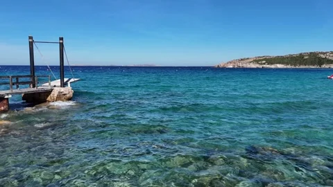 Drone Flying Forward Over Clear Turquoise Sea Toward a Wooden Dock Vídeo Stock 334062988