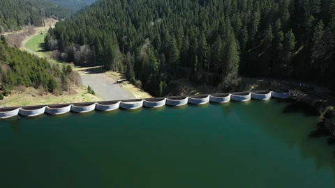 Drone flying forward over green lake toward dam in daylight, aerial landscape Video stock 333072569