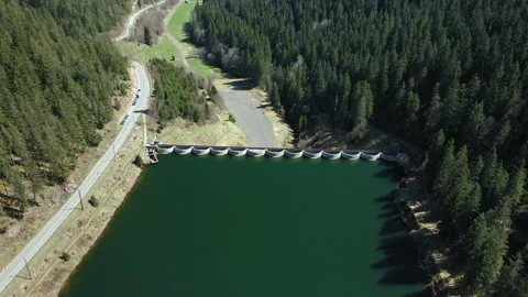 Drone flying forward over green lake toward dam in daylight, aerial landscape Video stock 333073057