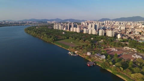 Drone flying forward over Gwangnaru Hangang Park towards Seoul city skyline and 库存影片 334768176